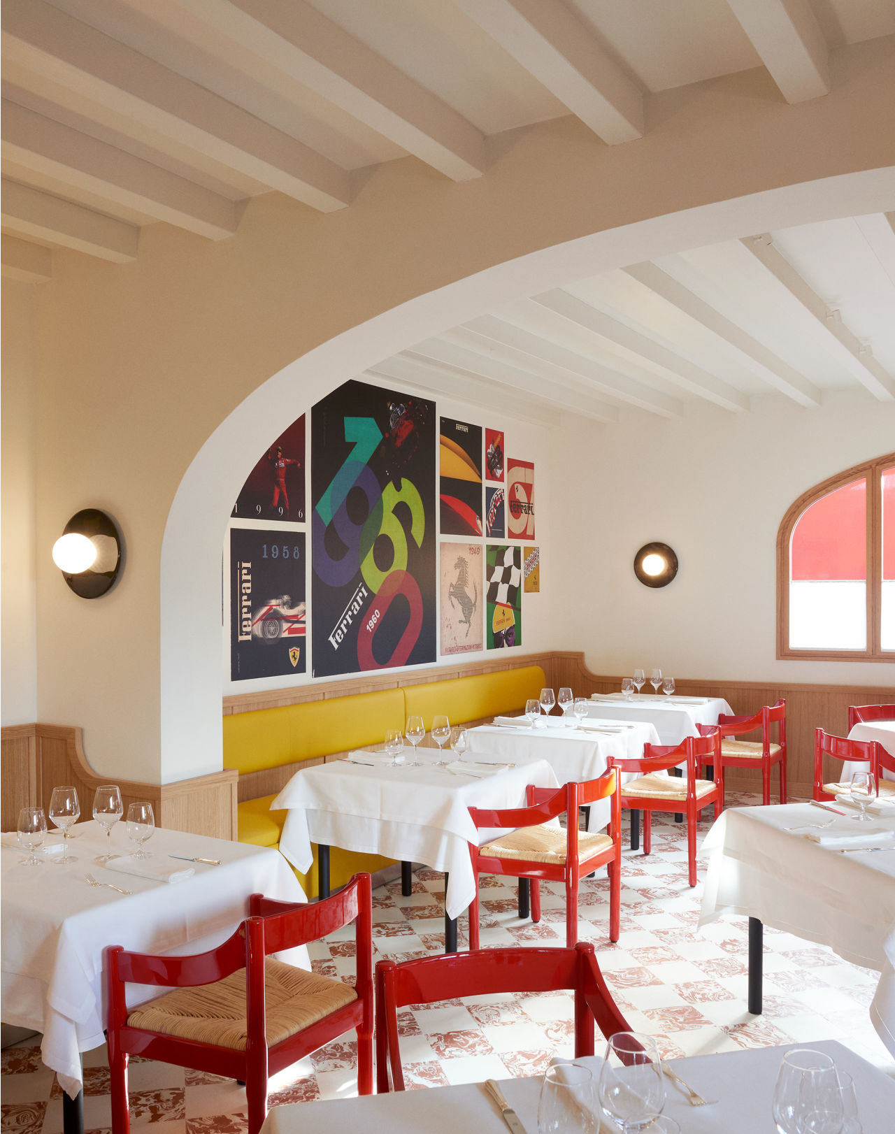 Cavallino 餐厅内部，黄色长椅、Ferrari 品牌装饰和白色餐桌