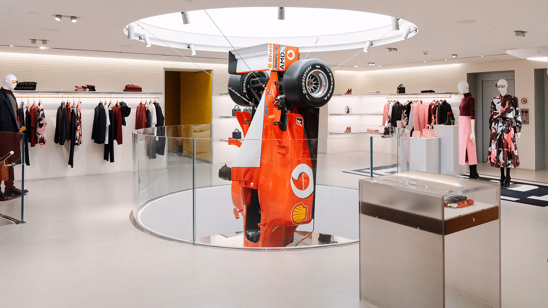 米兰旗舰店活动现场，Leclerc 和 Sainz 与车迷互动，周围陈列经典赛车服