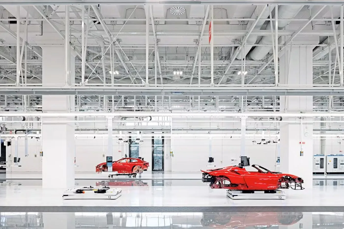 Ferrari E-Building 内部，白色机器人正在组装红色车身