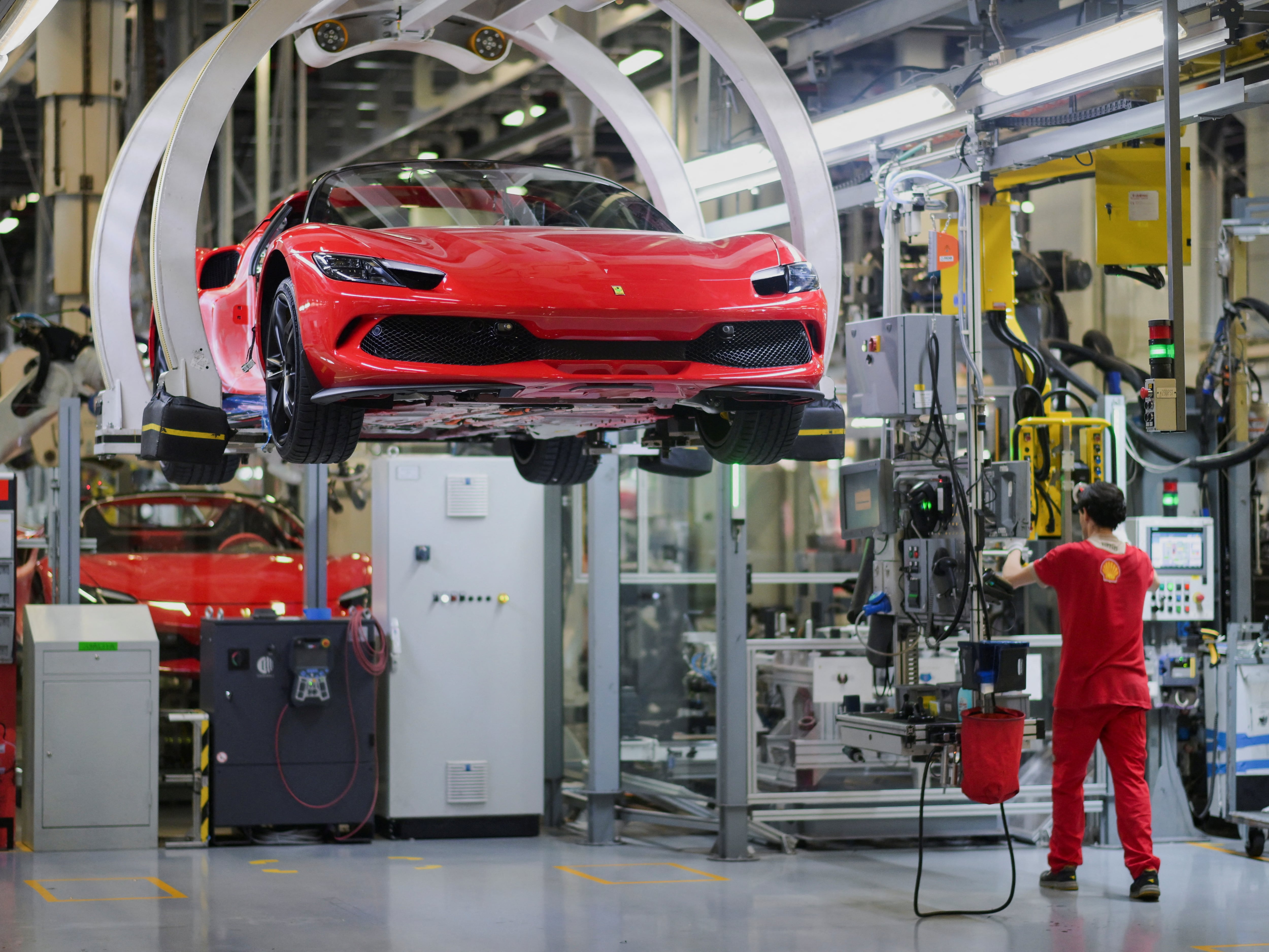 Ferrari Maranello 工厂的整车装配线，多台红色 Ferrari 车身在流水线上依次排列