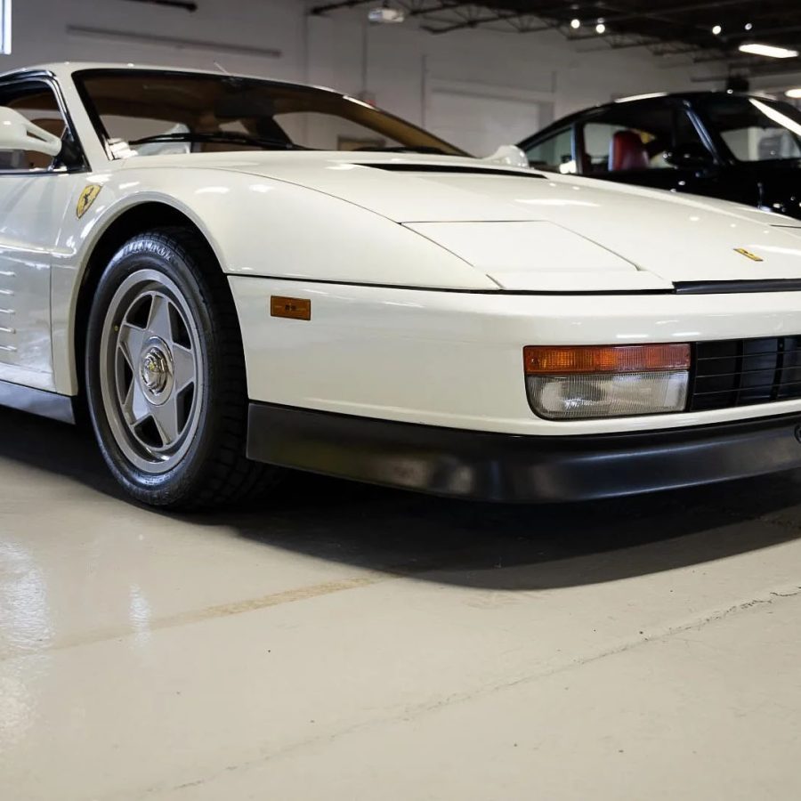 白色 Ferrari Testarossa 侧面外观，车身侧面的水平散热条和后部宽大的翼子板在展厅灯光下清晰可见