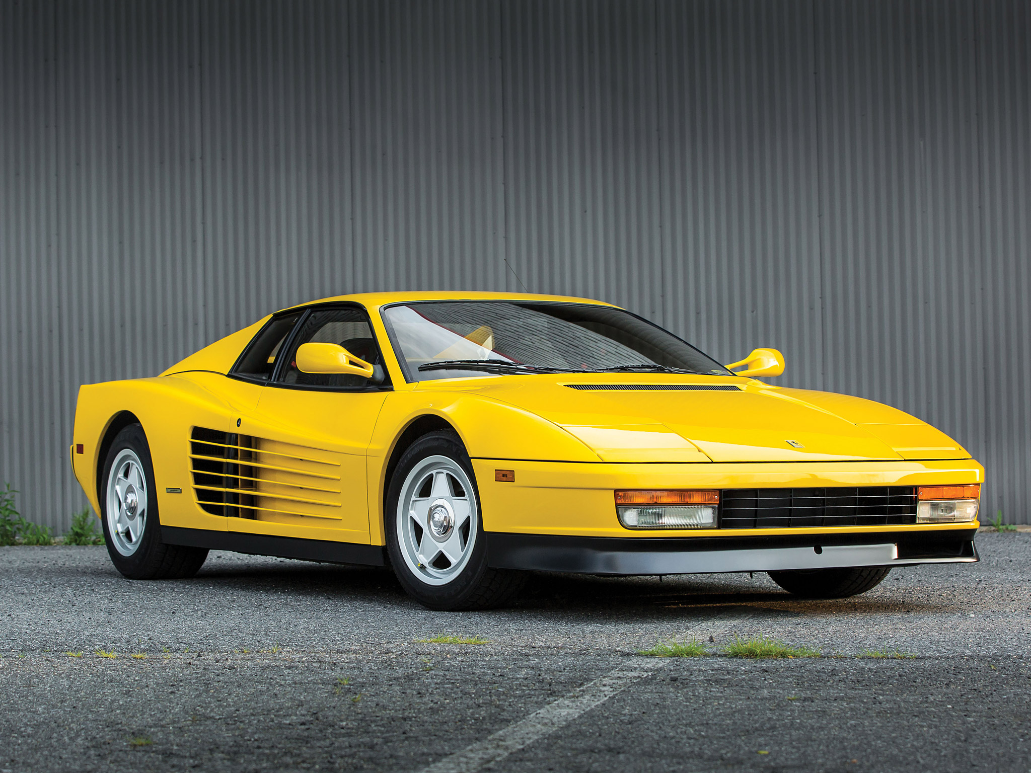 Ferrari Testarossa（红色）和 F512 M（黄色）并排停放，两代车型的轮廓对比。F512 M 改用固定头灯和圆形尾灯