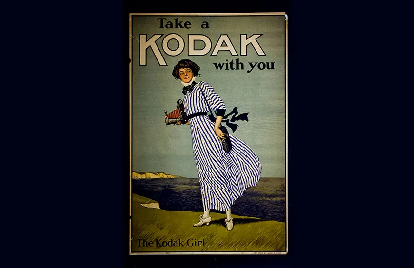 John Hassall 1910 年创作的 "Take a Kodak with you" 海报，女性站在多佛白崖上手持 Kodak 相机