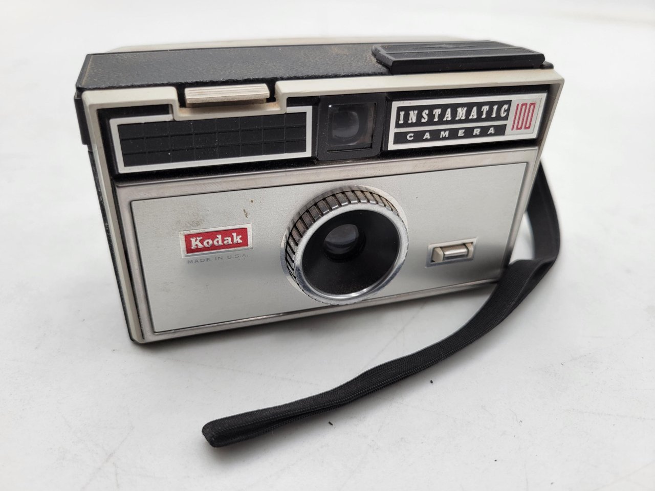 Kodak Instamatic 126 相机，浅灰色塑料机身，侧面可见凸出的过片扳手，上方有闪光灯座接口