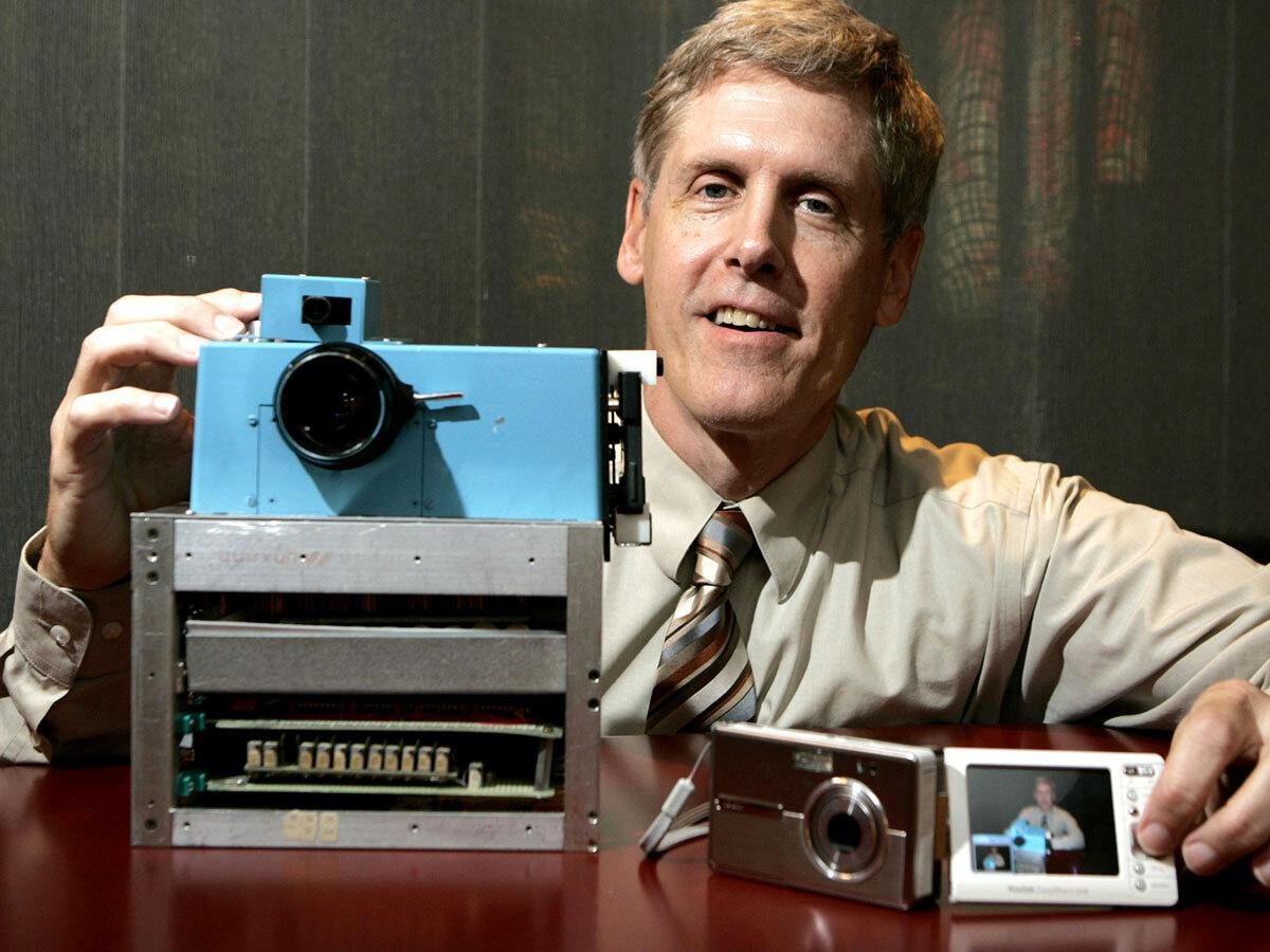 Steve Sasson 展示第一台数码相机原型，手边放着原型机和电视屏幕上的输出画面