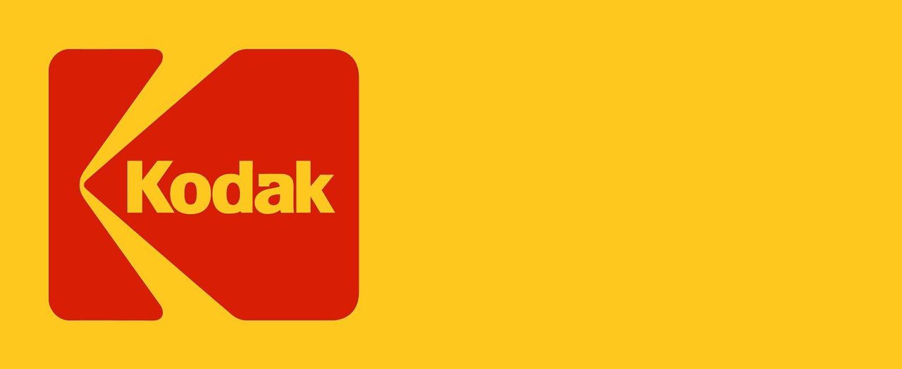 A collection of vintage Kodak yellow boxes spanning decades, showing consistent yellow+red packaging