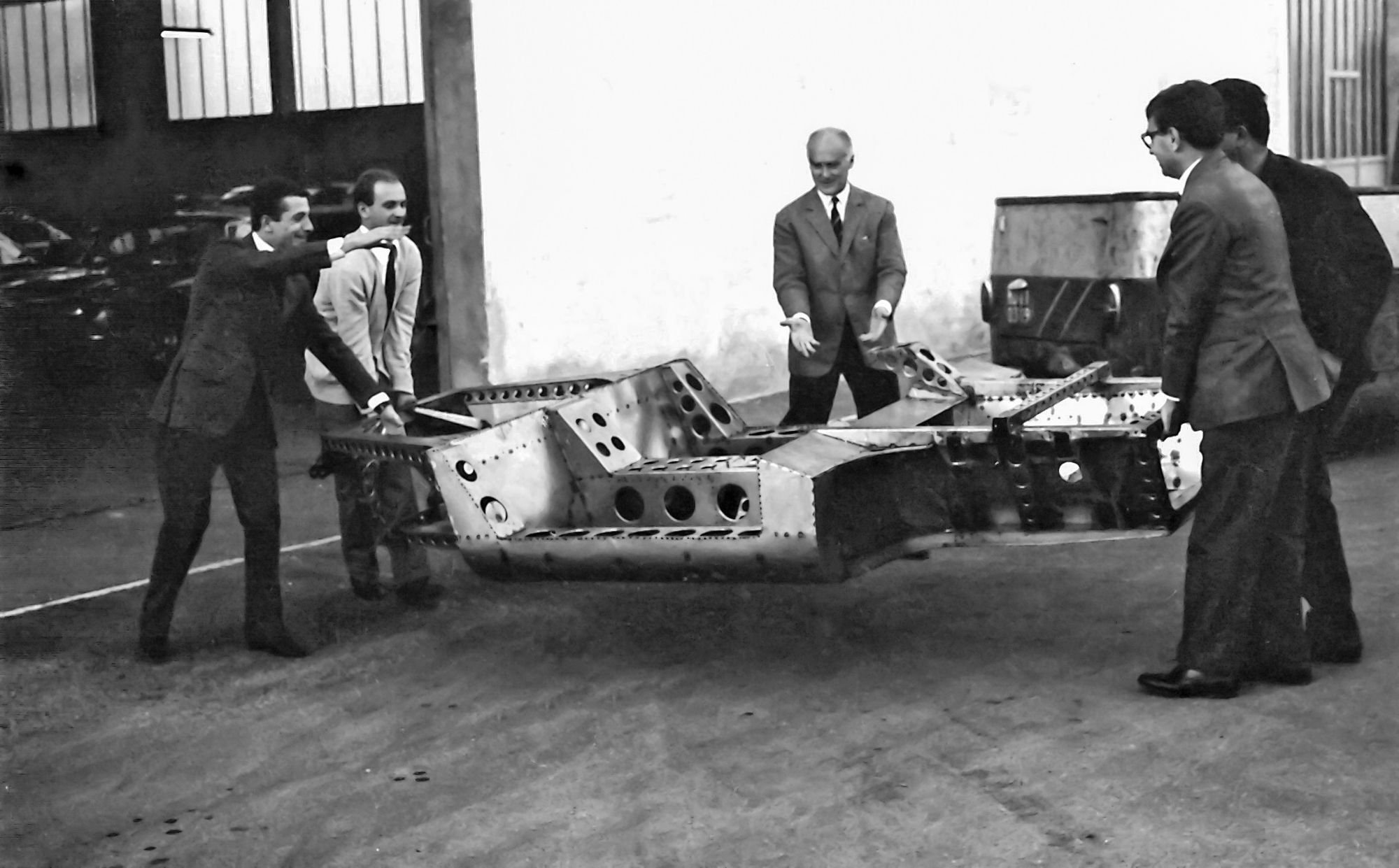 Gian Paolo Dallara（右）和 Paolo Stanzani（左）在都灵车展现场，与同事们一起抬起 TP400 底盘。两人当时分别 26 岁和 27 岁。