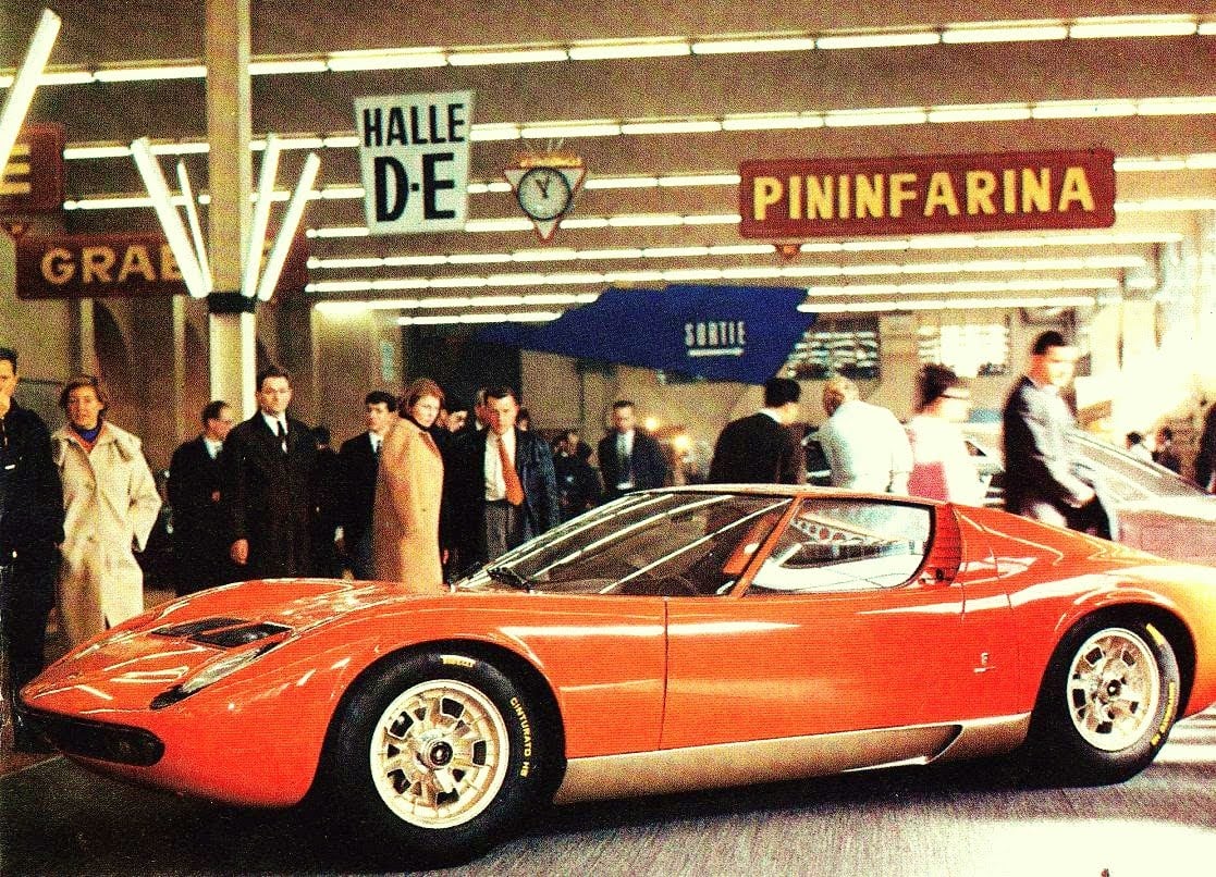 1966 年日内瓦车展上的 Miura P400，橙色车身吸引大量参观者围观。Miura 在这里被公认为全球首款量产中置引擎超跑。