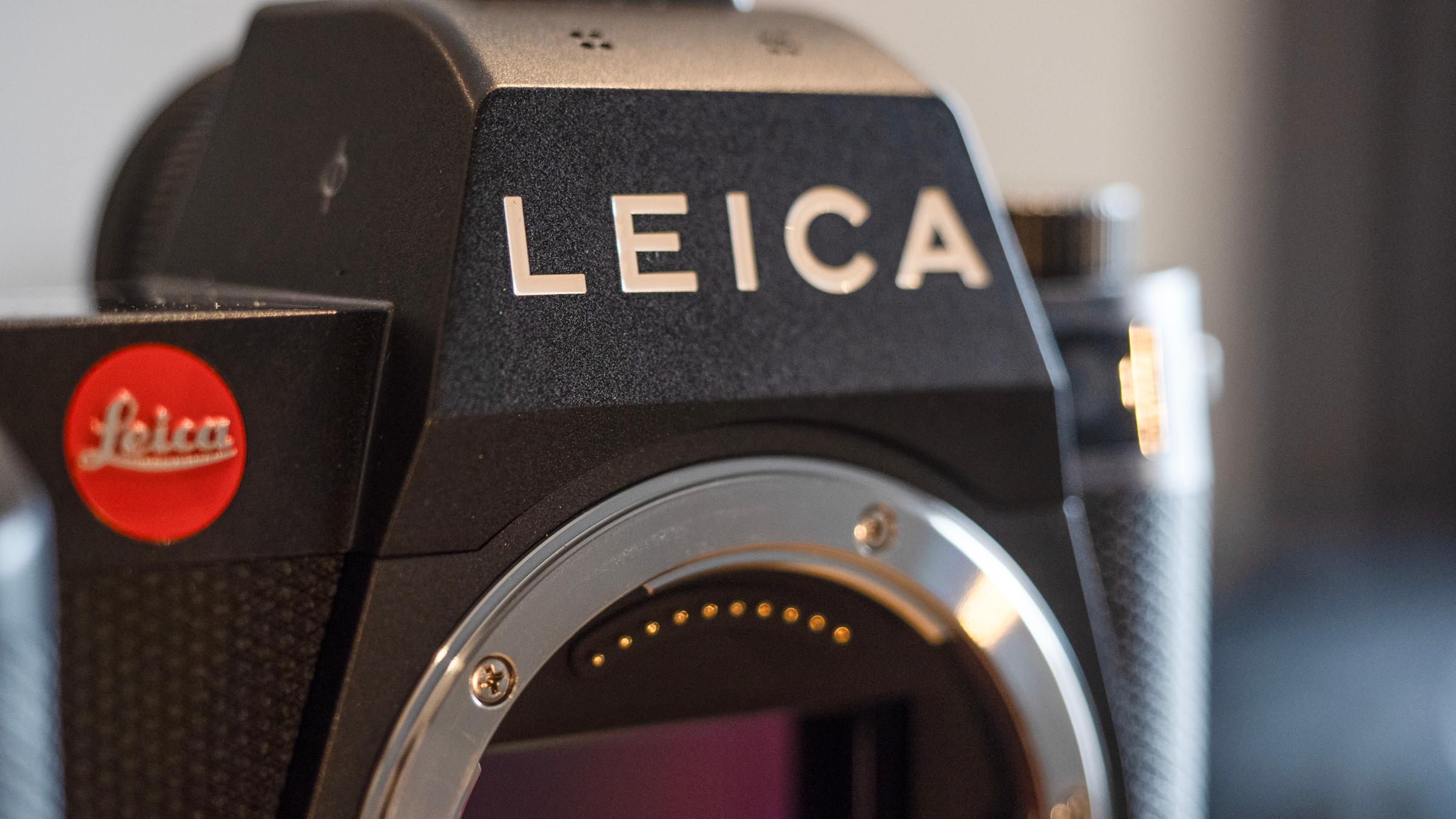 Leica CEO Matthias Harsch 站在品牌背景前，画面包含公司营收数据